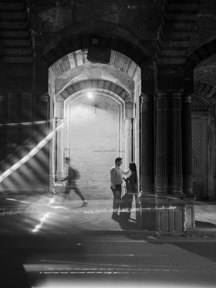 portfolio-img-03 Couple at night under an archway in a moody black and white setting.